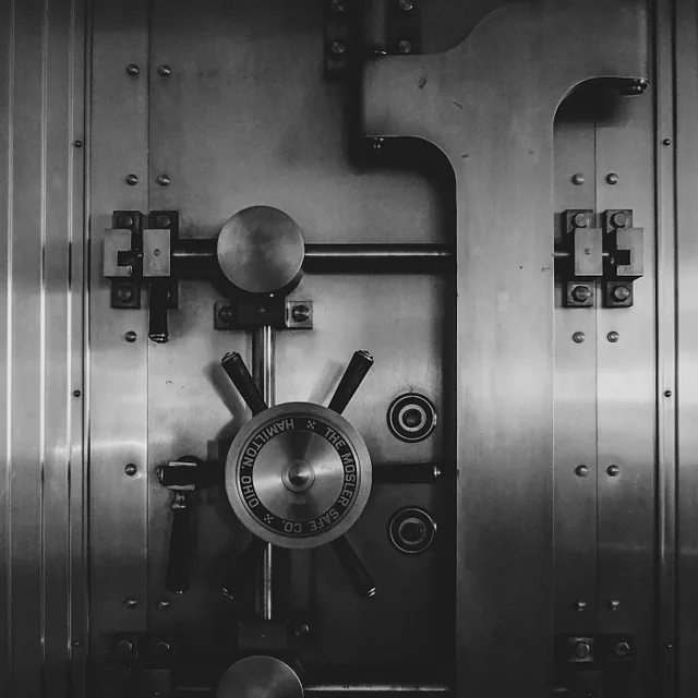 A locked bank vault. Black and White image, with a dial used for unlocking the vault.