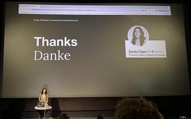 Seyda Uelgen, Principal Product Designer at Zalando stands in front of the audience, after finishing her talk, the screen behind her reads “Thanks. Danke.”