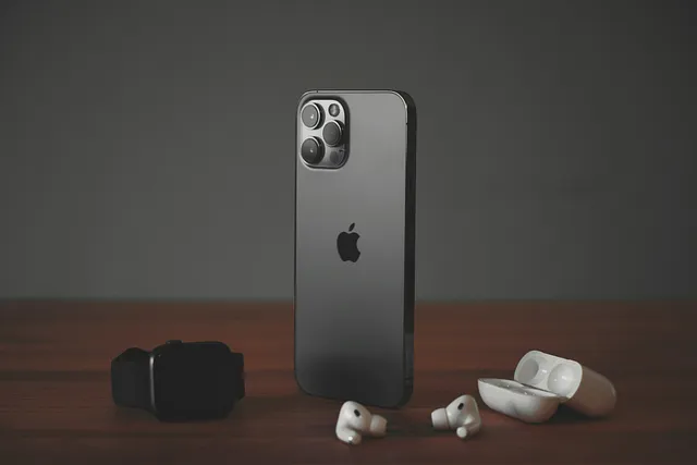 Sleek iPhone with a metallic finish stands upright, accompanied by AirPods and an Apple Watch, showcasing Apple’s premium tech accessories.